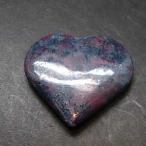 Peut inclure: Une pierre en forme de cœur avec une surface polie. La pierre présente un mélange de couleurs, notamment du bleu profond, du violet et des reflets argentés. Le cœur est lisse et semble être sculpté dans une seule pièce de pierre.