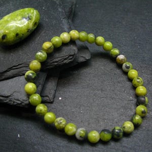 Peut inclure: Un bracelet en pierres précieuses vertes et noires avec des perles rondes. Le bracelet est fait de pierres naturelles et mesure environ 18 cm de long.