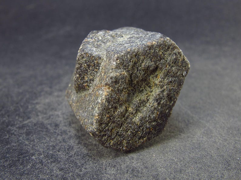 May include: A dark gray, cube-shaped rock with a rough, textured surface.