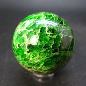 May include: A green aventurine sphere with a unique, mosaic-like pattern. The sphere is polished and has a glossy finish.