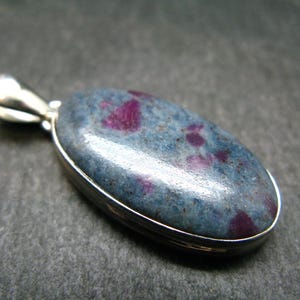 May include: A silver pendant featuring a blue and pink gemstone. The gemstone has a speckled pattern and is set in a silver bezel.
