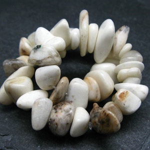 May include: A white and brown stone bracelet with a variety of shapes and sizes. The stones are smooth and polished.