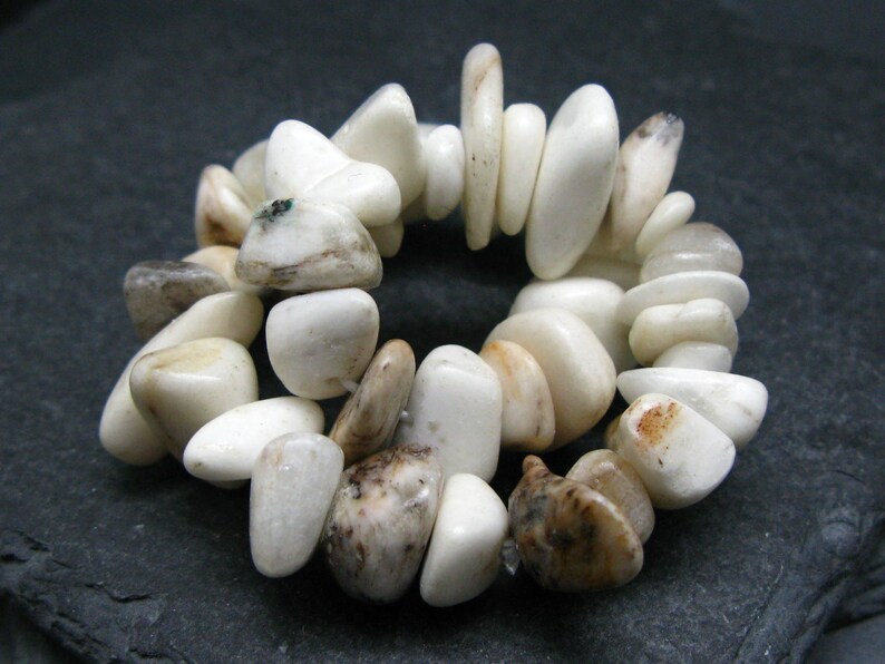 May include: A white and brown stone bracelet with a variety of shapes and sizes. The stones are smooth and polished.