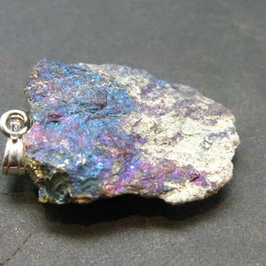 May include: A raw, iridescent, blue, purple, and silver gemstone pendant with a silver bail.