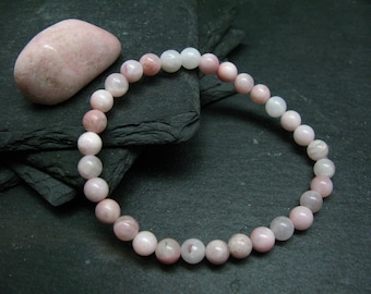 Könnte beinhalten: Ein rosa-weißes Edelstein-Armband mit runden Perlen. Das Armband besteht aus natürlichen Steinen und ist etwa 18 cm lang.