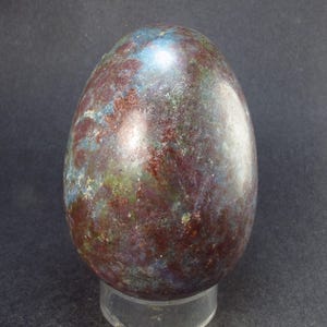 May include: A smooth, polished egg-shaped stone with a swirling pattern of red, blue, green, and white.