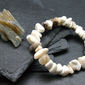 May include: A white and brown stone bracelet with a cluster of light blue and brown crystals.