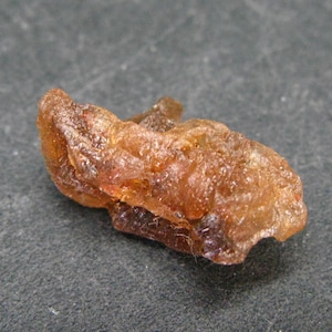 May include: A piece of amber, a fossilized tree resin, with a translucent, orange-brown color and a rough, irregular shape.
