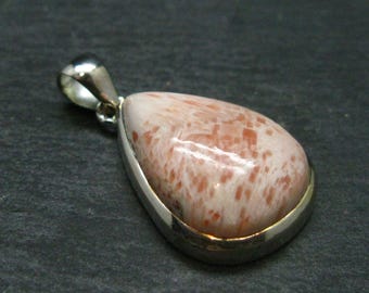 Op de afbeelding: Een traanvormige hanger met een roze en oranje sunstone, gezet in een zilveren bezel. De hanger heeft een zilveren bail om aan een ketting te bevestigen.