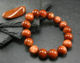 May include: A brown gemstone bracelet with round beads. The bracelet is made of natural sandstone and has a polished finish.