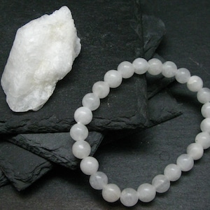 Peut inclure: Un bracelet en pierres blanches avec des perles rondes sur un fond noir.