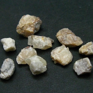 May include: A collection of small, rough, translucent, light brown and white crystals. The crystals are various shapes and sizes.