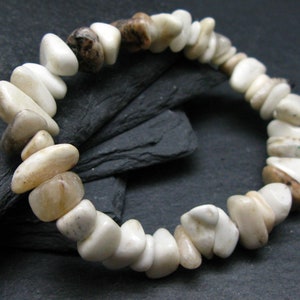 May include: A white and brown stone bracelet with a variety of shapes and sizes. The bracelet is made of natural stones and has a rustic look.