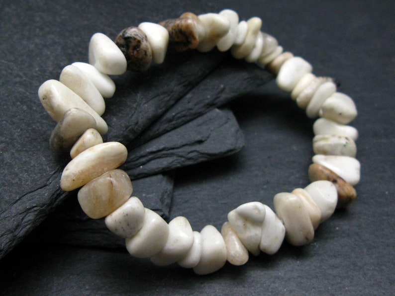May include: A white and brown stone bracelet with a variety of shapes and sizes. The bracelet is made of natural stones and has a rustic look.