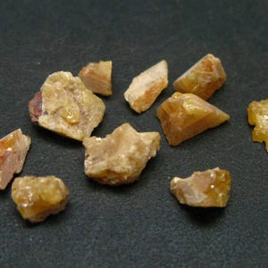 May include: A collection of small, translucent, yellow-orange crystals with a rough, irregular texture.