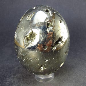 May include: A smooth, golden pyrite sphere with a metallic sheen. The sphere is covered in small, irregular pyrite crystals, giving it a textured surface.