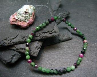 May include: A green and pink gemstone bracelet with round beads. The bracelet is made of green, pink, and black beads.