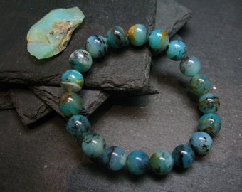Könnte beinhalten: Ein blaues und grünes Edelstein-Armband mit einer Mischung aus dunkelblauen und hellblauen Perlen. Die Perlen sind rund und haben eine natürliche, polierte Oberfläche.