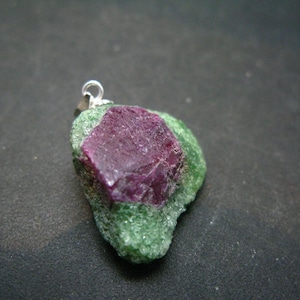 May include: A green and pink gemstone pendant with a silver bail. The gemstone is rough and has a natural, irregular shape.