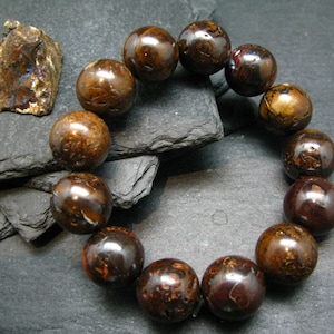 May include: A bracelet made of brown and black opal beads. The beads are round and have a smooth, polished finish. The bracelet is approximately 20 cm in length.