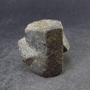 May include: A dark gray, irregularly shaped, crystal with a rough, textured surface. The crystal is a geometric shape with multiple facets.