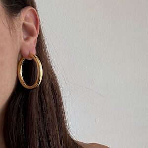 Brincos de argola grandes dourados, com 40 mm de largura.