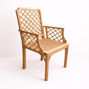 A wooden chair with a woven cane seat and a diamond-shaped lattice back. The chair is light brown and has a simple, elegant design.