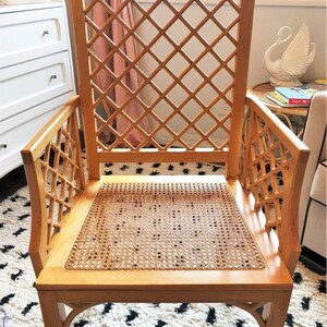 A wooden chair with a woven cane seat and a diamond-shaped lattice back. The chair is light brown and has a simple, elegant design.