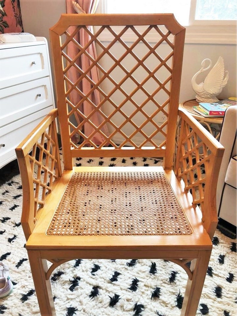 A wooden chair with a woven cane seat and a diamond-shaped lattice back. The chair is light brown and has a simple, elegant design.