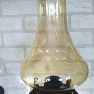 An amber glass lampshade with a brown base. The lampshade is round and has a wide opening at the top. The base is made of wood and has a dark brown finish.