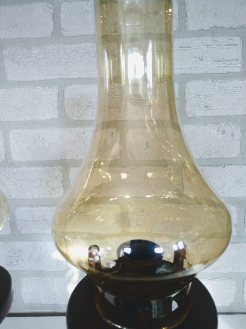 An amber glass lampshade with a brown base. The lampshade is round and has a wide opening at the top. The base is made of wood and has a dark brown finish.