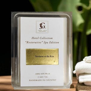May include: A clear plastic container holding a white label with gold lettering. The label reads "Hotel Collection 'Restorative' Spa Edition" and "Nocturne at the Ritz." The product is 100% soy wax, 2.5oz/72g, and handmade.