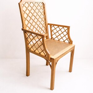 A wooden chair with a woven cane seat and a diamond-shaped lattice back. The chair is light brown and has a simple, elegant design.
