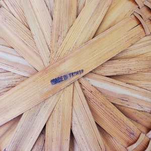 May include: Close-up of a woven basket base made of light brown bamboo strips. The strips are arranged in a radial pattern, with the text "MADE IN TAIWAN" printed in black ink.