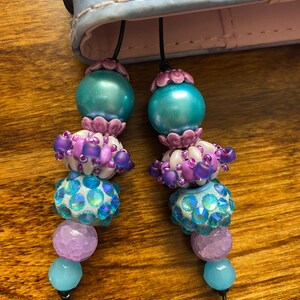 May include: Two teal blue and purple beaded bookmarks with a crystal bead and a light blue bead at the bottom.