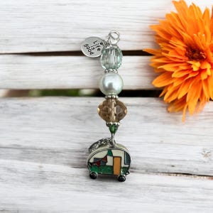 May include: A charm bracelet with a silver camper charm, green and white beads, a brown crystal bead, and a silver charm that says "Life is good".