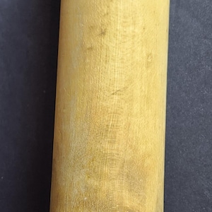 May include: A wooden rolling pin with a light finish. The rolling pin has a cylindrical body and rounded handles. It is a kitchen tool used for flattening dough, measuring approximately 25 cm in length.