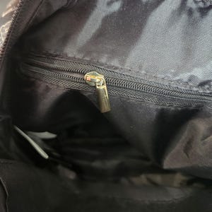 Peut inclure: Une tasse en c&eacute;ramique blanche avec une anse noire et le texte "But First, Coffee" en noir, dans une police manuscrite. La tasse est pos&eacute;e sur une surface blanche.