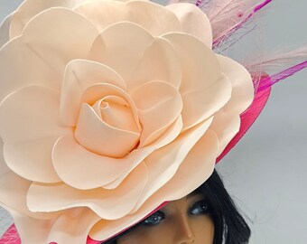 Könnte beinhalten: Ein pfirsichfarbener Blumenhut mit leuchtend pinkfarbener Krempe und Akzenten. Der Hut hat ein großes, mehrschichtiges Blumendesign, zarte Netze und Federverzierungen. Ideal für besondere Anlässe.