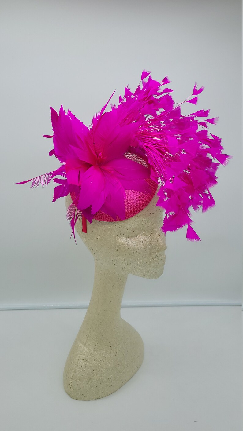 May include: A bright pink fascinator with a large flower and feathers.