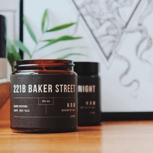 May include: A brown glass candle jar with a black label that reads "221B Baker Street" and "H.O.W. House of Wax". The candle is hand-poured soy wax and is number 04 in the collection.