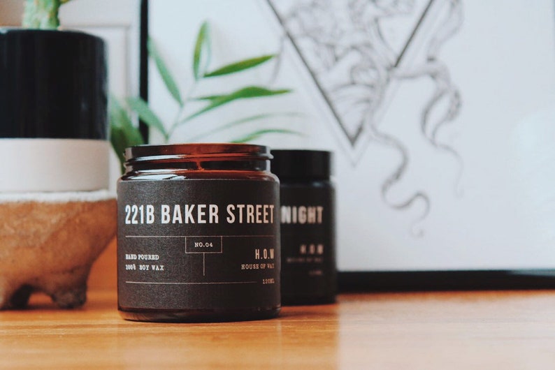 May include: A brown glass candle jar with a black label that reads "221B Baker Street" and "H.O.W. House of Wax". The candle is hand-poured soy wax and is number 04 in the collection.