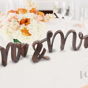 May include: Wooden "Mr. & Mrs." sign in a rustic brown finish. The sign is perfect for a wedding or anniversary celebration.