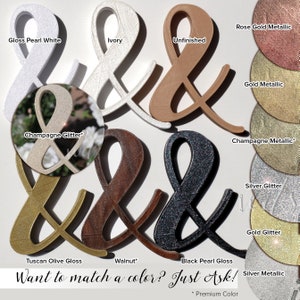 May include: A variety of ampersand signs in different colors and finishes, including gloss pearl white, ivory, unfinished, rose gold metallic, gold metallic, champagne glitter, champagne metallic, silver glitter, gold glitter, Tuscan olive gloss, walnut, black pearl gloss, and silver metallic. The text "Want to match a color? Just Ask!" is at the bottom of the image.