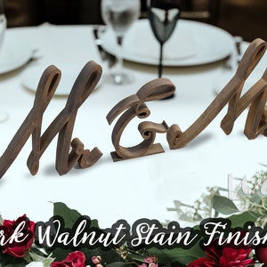 May include: Wooden "Mr & Mrs" wedding sign with a dark walnut stain finish. The sign is made of two separate pieces, one for "Mr" and one for "Mrs".