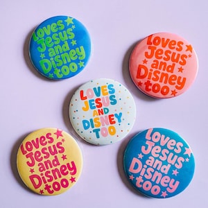 May include: Five circular pinback buttons featuring the text "Loves Jesus and Disney too" with small star accents. The buttons come in various colors including blue with green text, pink with red text, white with multicolored text, yellow with pink text, and blue with pink text.