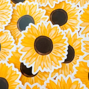 May include: A collection of yellow sunflower stickers with brown centers. The stickers are arranged in a random pattern and are all facing the same direction.