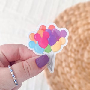 May include: A sticker of a bunch of colourful balloons with Mickey Mouse ears. The balloons are red, orange, yellow, green, blue, purple and pink.