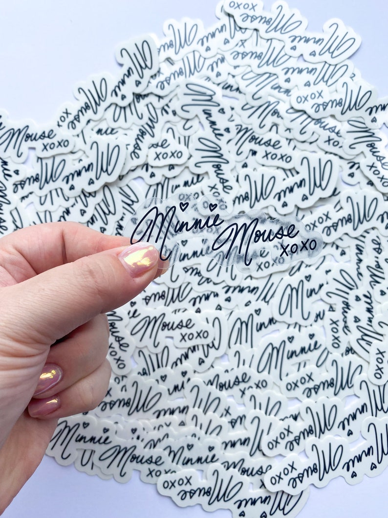 Op de afbeelding: Een close-up van een stapel witte stickers met zwarte tekst die "Minnie Mouse xoxo" zegt.