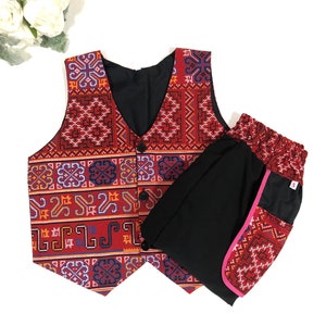 May include: A two-piece outfit featuring a vest and pants. The vest has a red, patterned design with black buttons and a black interior. The pants are black with a patterned cuff and pink trim. The outfit is displayed on a white background.